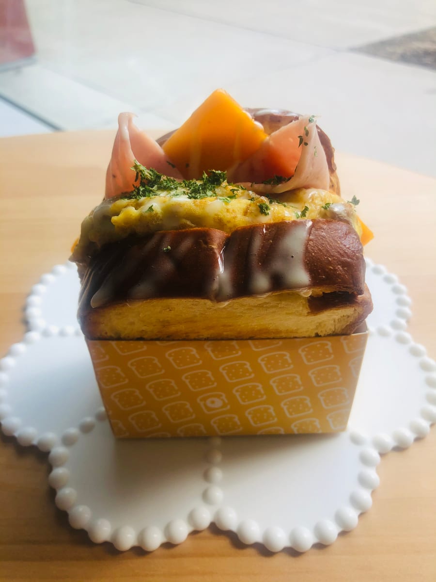 Egg sandwich topped with ham and cheese on a white plate