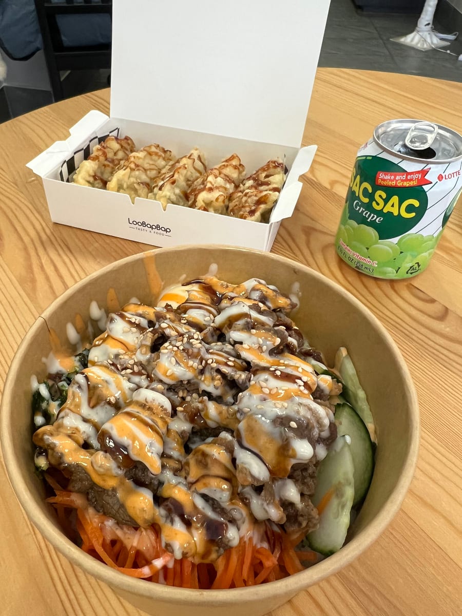 Cupbap topped with sauce and sesame seeds over carrot and cucumber