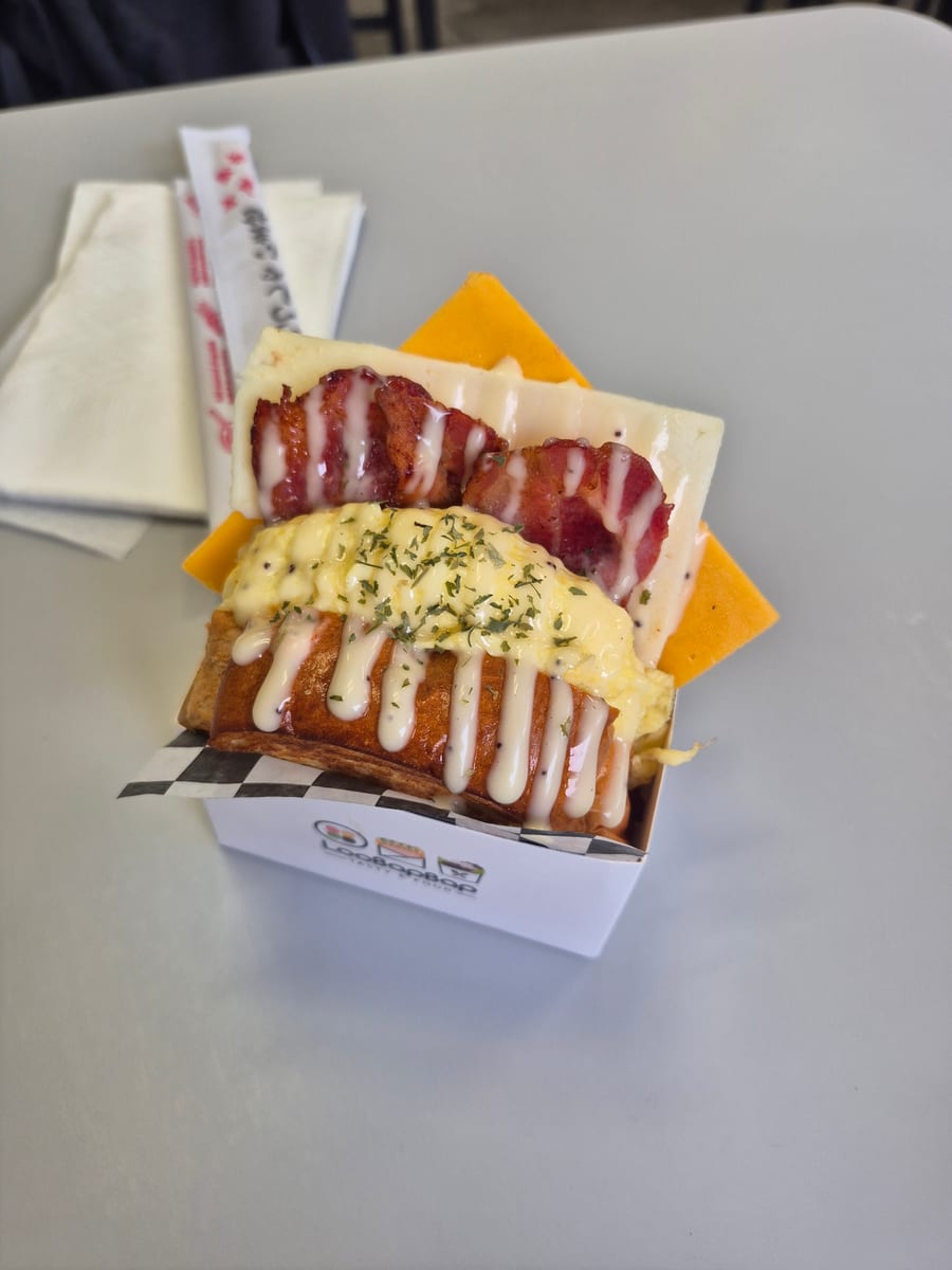 Egg toast sandwich with bacon and two cheeses in a LooBapBap box