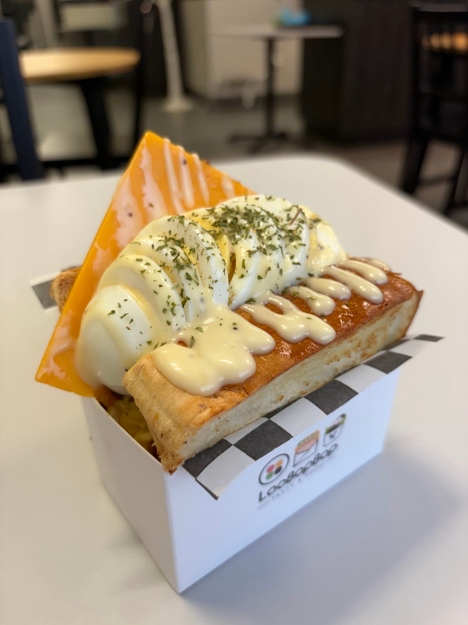 Egg toast sandwich with sliced egg and cheese in a LooBapBap box
